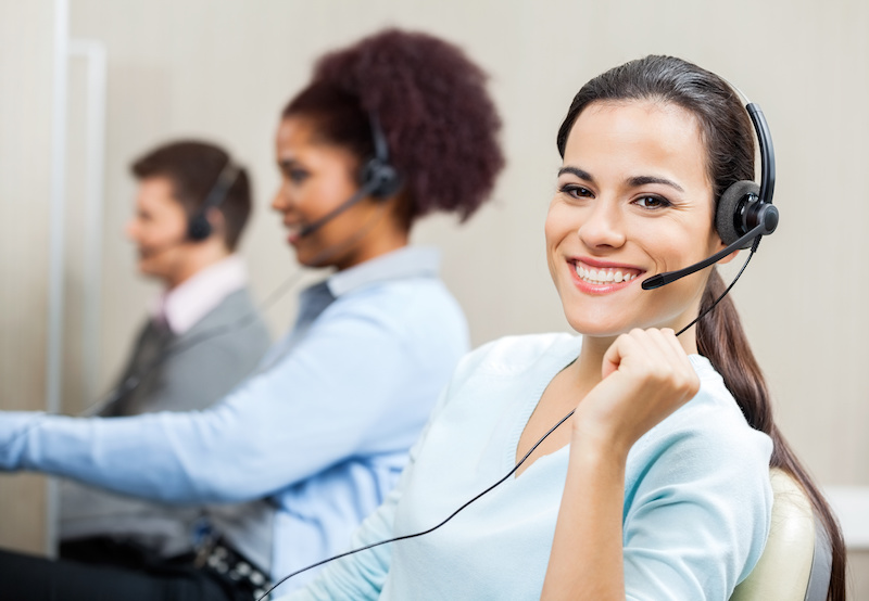 Portrait of smiling customer service representative with colleagues in background at office