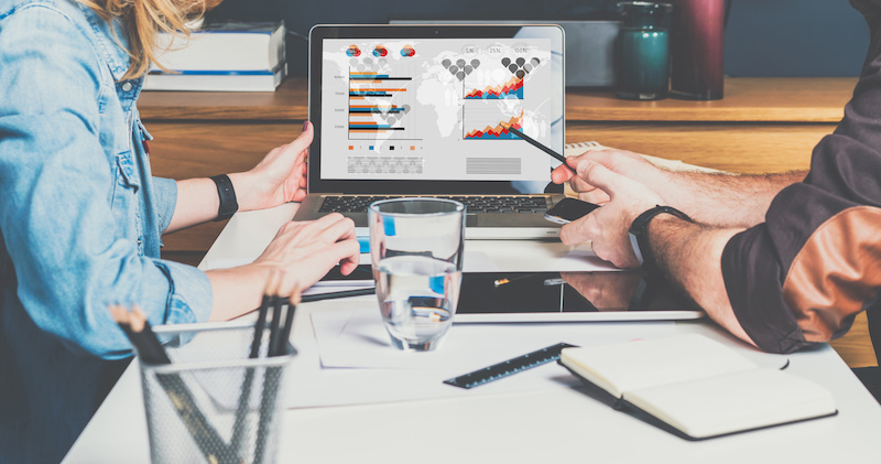 Business meeting. Teamwork. Businessman and businesswoman sitting at table in front of laptop and working. Man shows pencil on computer screen.Graphs,charts and diagrams on PC screen.Online education.