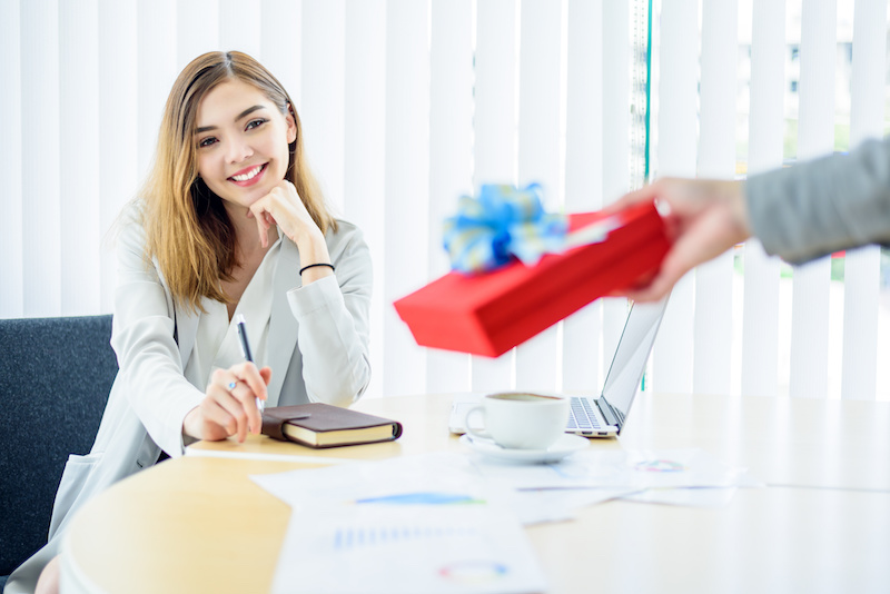 Happy smart Business woman looking red gift box in boss hand in modern office room