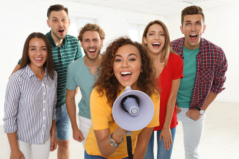 Group of happy young people with megaphone indoors