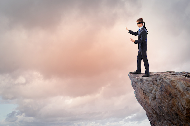 Man in blindfold on edge of cliff