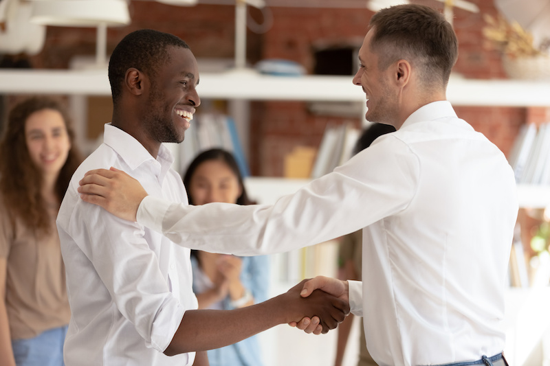 Executive boss handshaking promoting successful happy african black worker expressing gratitude praising shaking hand appreciating for good work, reward recognition acknowledgement concept