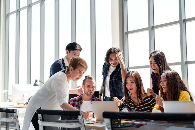 Group of People Team smiling and excited in success work with laptop at modern office. Creative Multiethnic or diverse teamwork feeling happy, enjoy and engaged with achievement project.