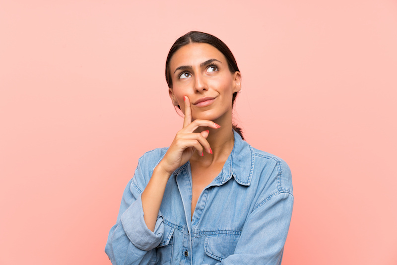Young woman over isolated pink background thinking an idea