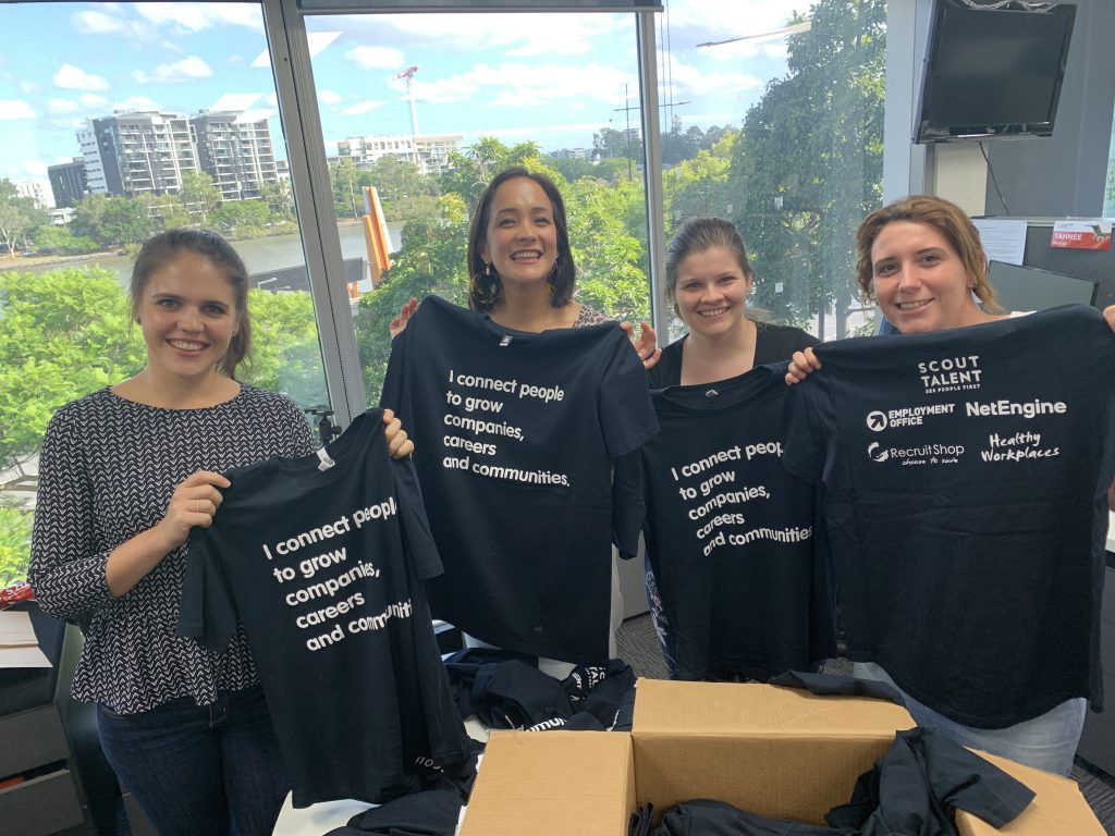Four Scout Talent team members showcasing Scout Talent's "company purpose" t-shirts