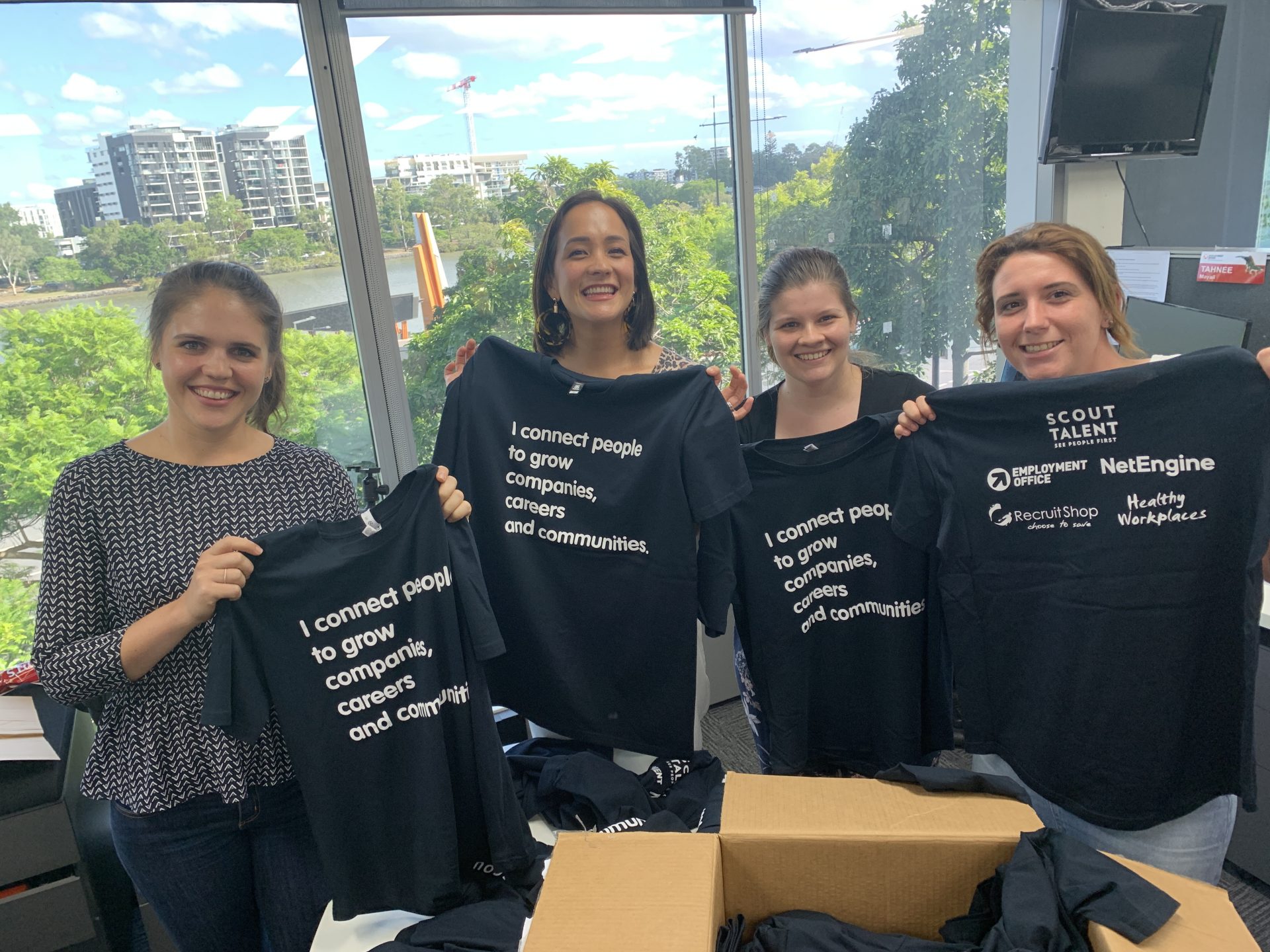 Four Scout Talent team members showcasing Scout Talent's "company purpose" t-shirts