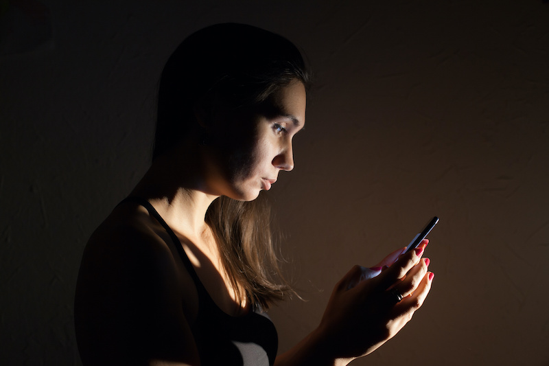 Cyberbullying woman looking at phone in the dark